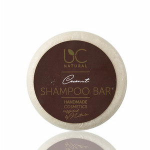 Natuurlijke kokosnoot shampoo bar van UC Natural. De shampoo heeft een ronde vorm met licht beige kleur en zit verpakt in een doorzichtige folie met donkerbruin etiket. De foto heeft een witte achtergrond.